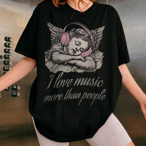 Camiseta Preta Unisex Design com Anjo com Fones de Ouvido Texto 
